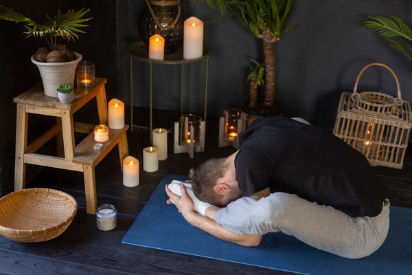 A man practicing a yoga pose indoors in relaxed clothing, illustrating the grounding movement practices that help balance Vata.