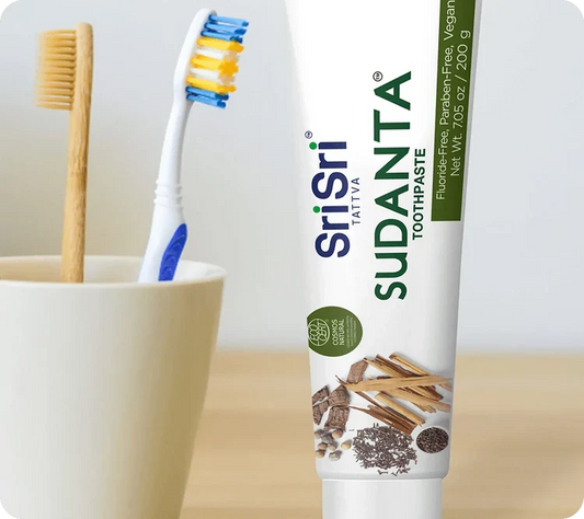 Sudanta toothpaste tube standing beside bamboo and manual toothbrushes in a cup